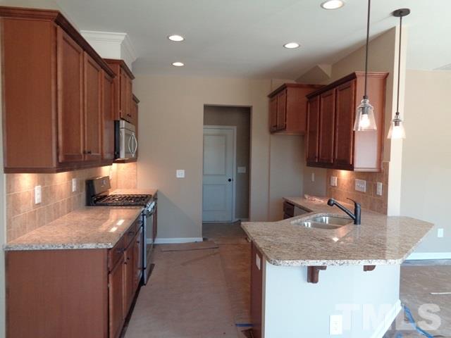 111 Torpoint Road Durham, NC 27703 - Photo 3 of 25 a kitchen with stainless steel appliances granite countertop wooden cabinets a sink and a stove