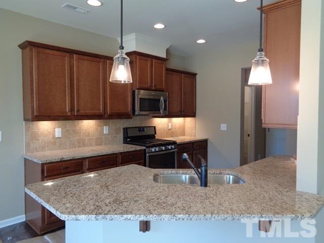 111 Torpoint Road Durham, NC 27703 - Photo 9 of 25 a kitchen with kitchen island granite countertop a sink a counter top space appliances and cabinets