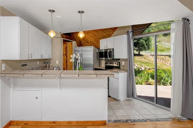 a kitchen with kitchen island a counter top space a sink stainless steel appliances and cabinets