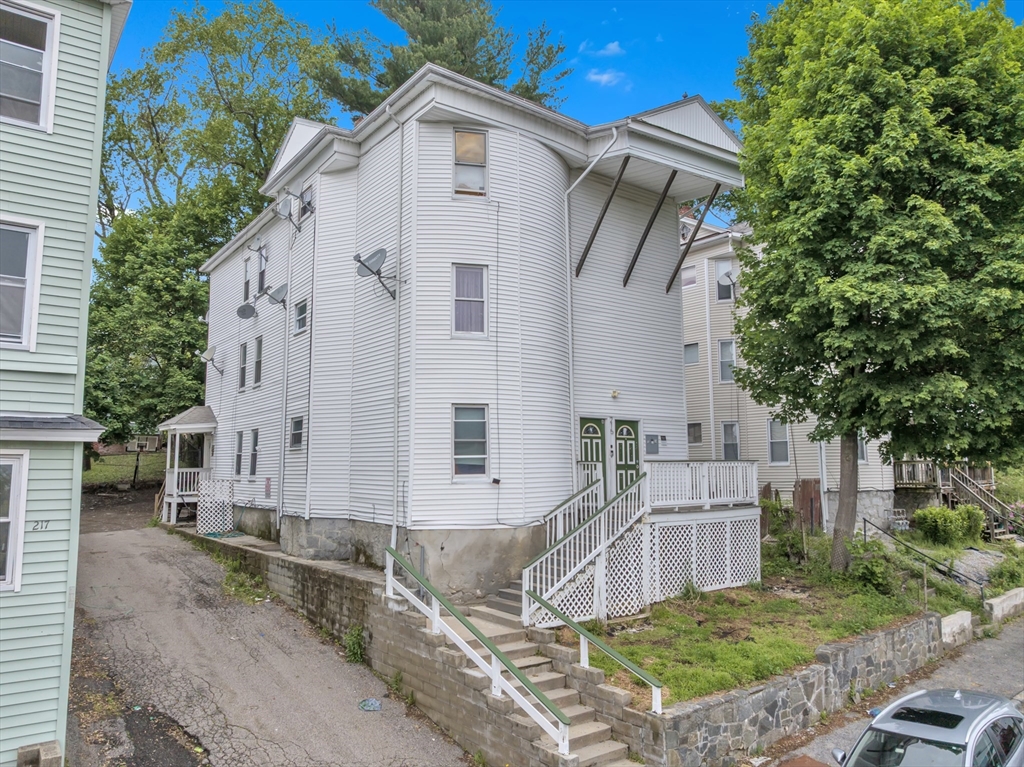 215 Beacon Street Worcester, MA 01610 - Photo 1 of 24 a view of a white house with large windows and a small yard