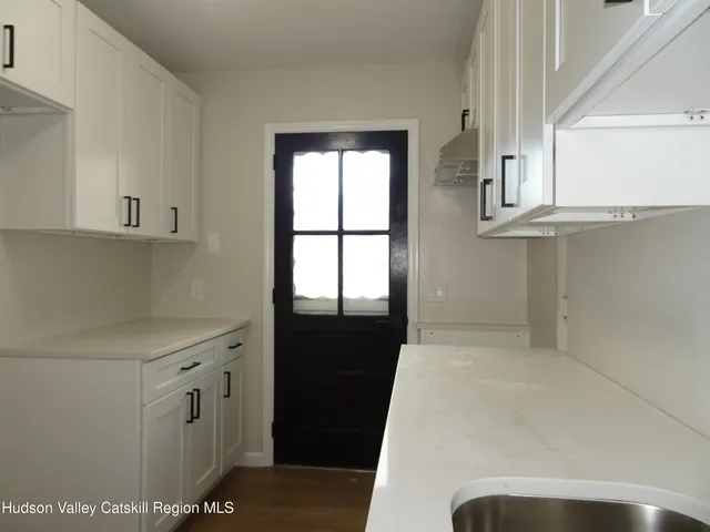 a view of a kitchen with white cabinets and a window