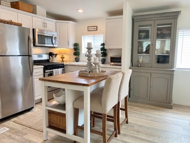 123 Jasper Street, Unit 23 Encinitas, CA 92024 - Photo 10 of 23 a kitchen with stainless steel appliances granite countertop a dining table chairs refrigerator and microwave