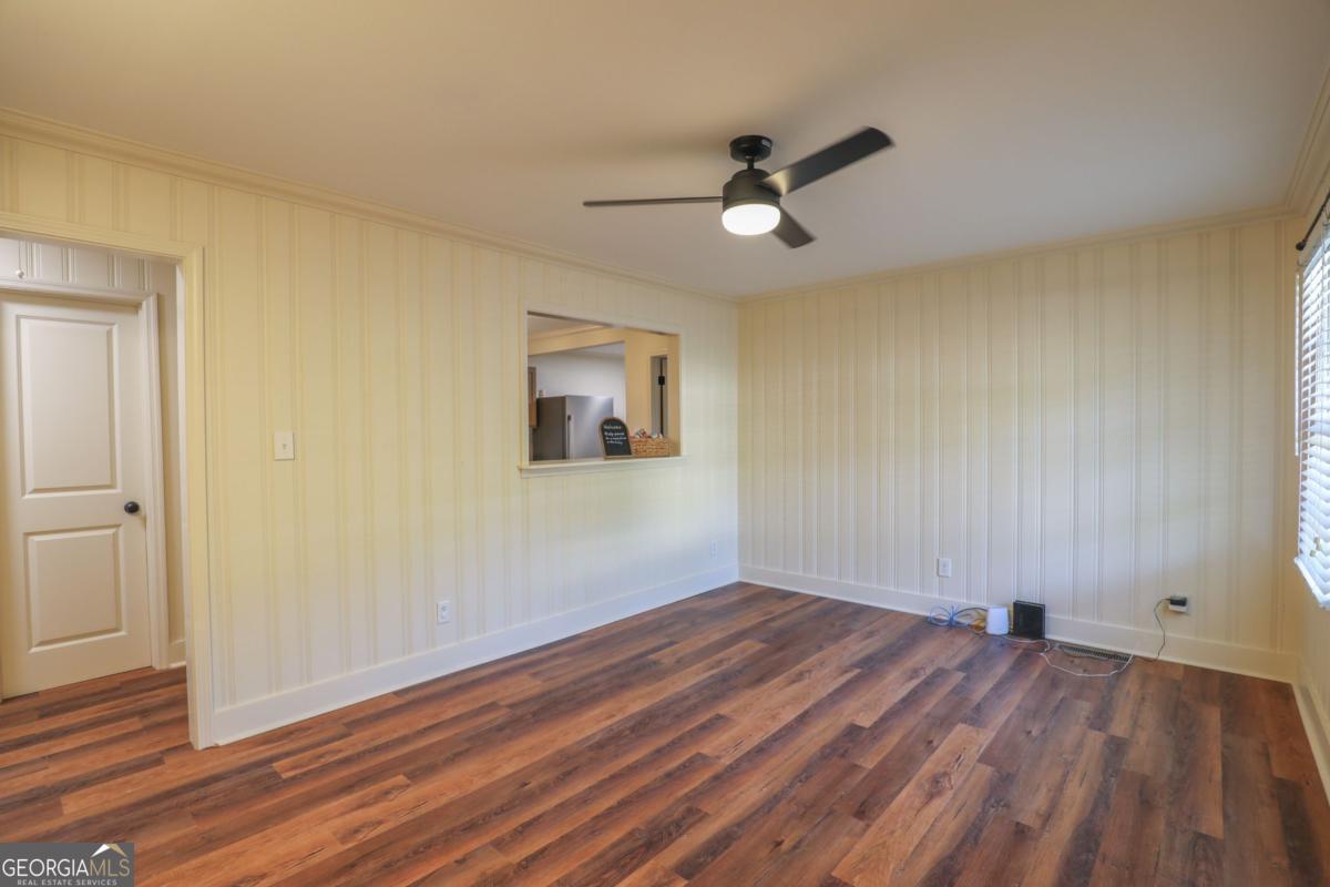 127 Fourth Street Southwest Milledgeville, GA 31061 - Photo 7 of 28 an empty room with wooden floor fan and windows