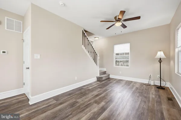 a view of empty room with wooden floor and fan