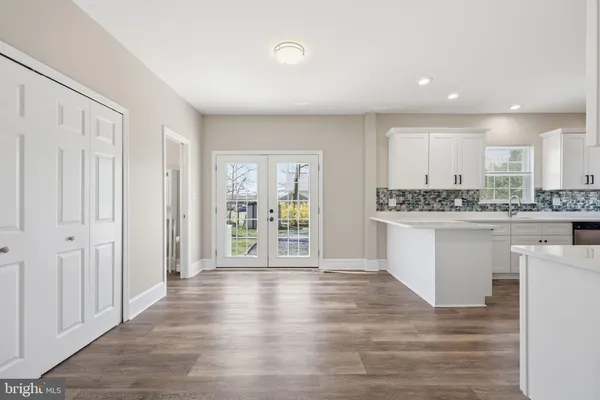 a large white kitchen with kitchen island a sink dishwasher stove and white cabinets with wooden floor