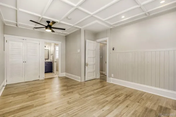 an empty room with wooden floor fan and windows