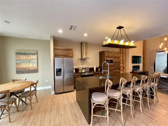 a kitchen with stainless steel appliances a dining table chairs stove refrigerator and cabinets