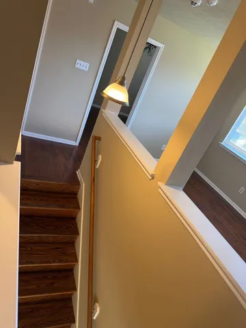 a view of a hallway with wooden floor and a bathroom