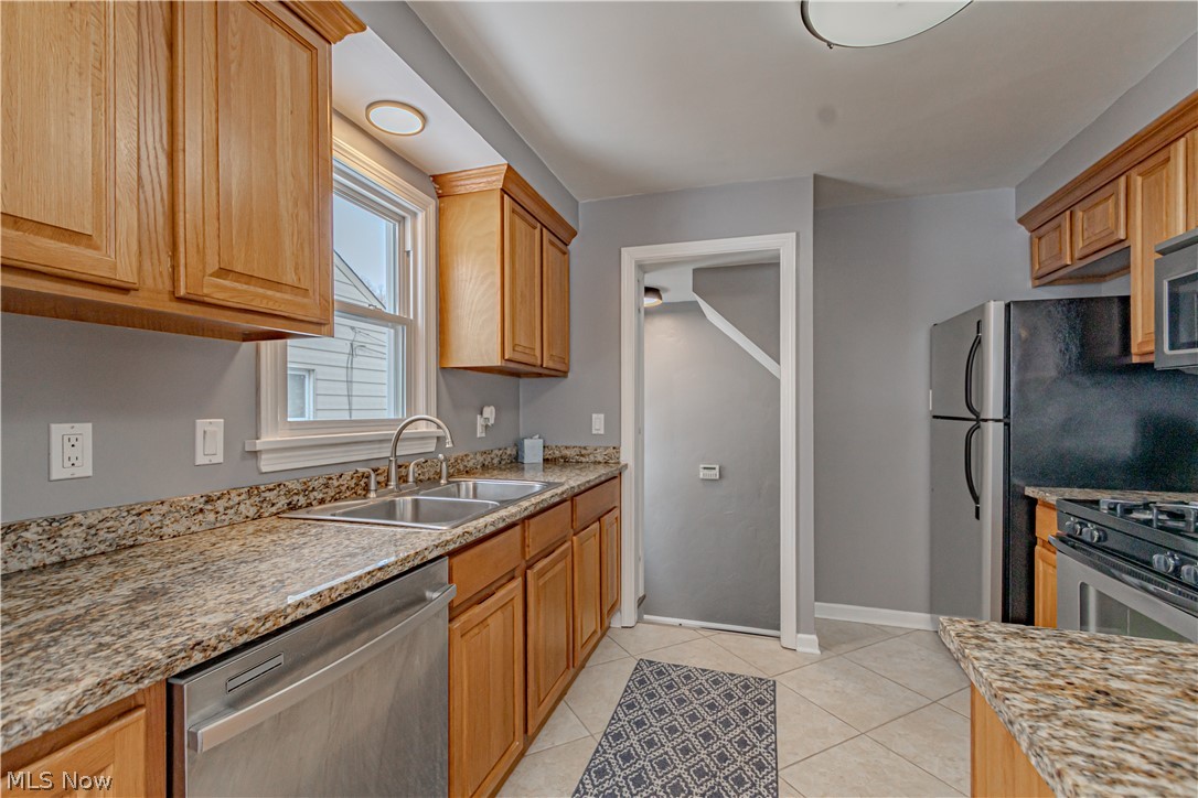 4157 Verona Road Cleveland, OH 44121 - Photo 4 of 26 Kitchen featuring light stone countertops, stainless steel appliances, light tile patterned flooring, and wood finish cabinets