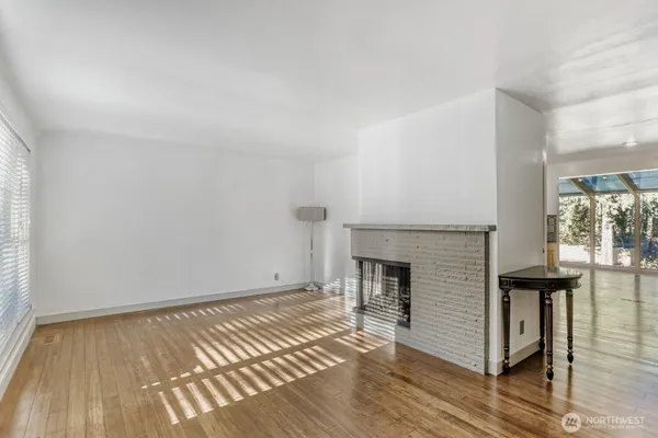 an empty room with wooden floor fireplace and windows