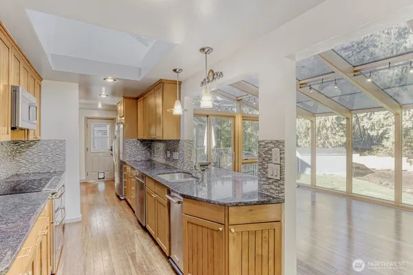a kitchen with stainless steel appliances granite countertop a sink a stove and a wooden floors