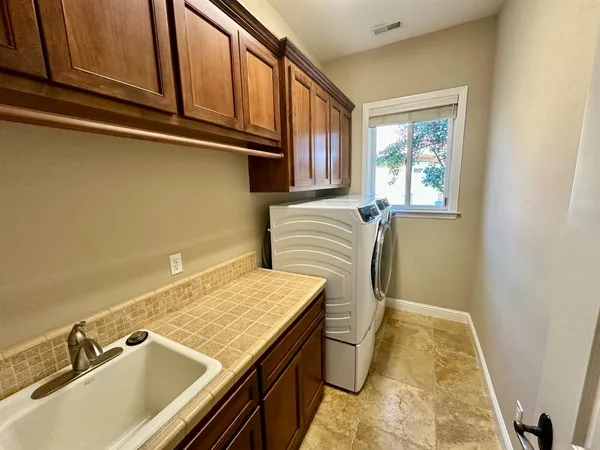 a bathroom with a granite countertop sink and a washing machine