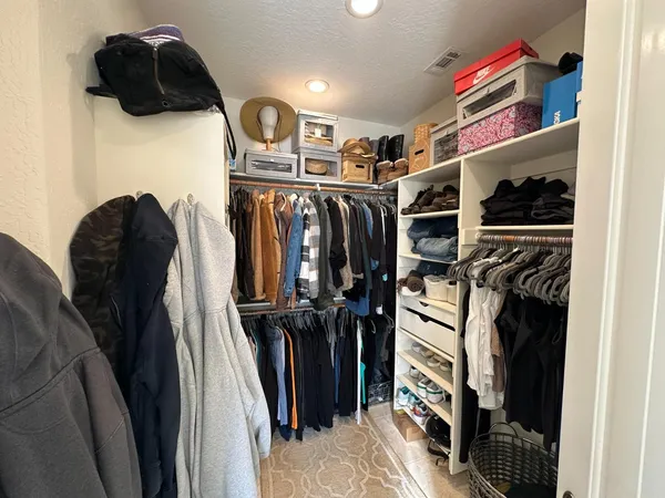 a view of walk in closet with clothes and shoes