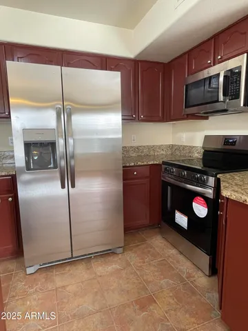 a large kitchen with stainless steel appliances granite countertop a stove top oven a sink dishwasher and a refrigerator