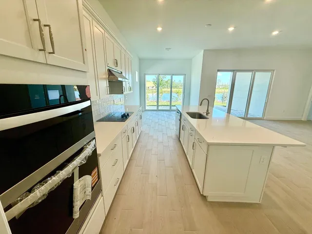 a view of a kitchen with stainless steel appliances a sink and wooden floor