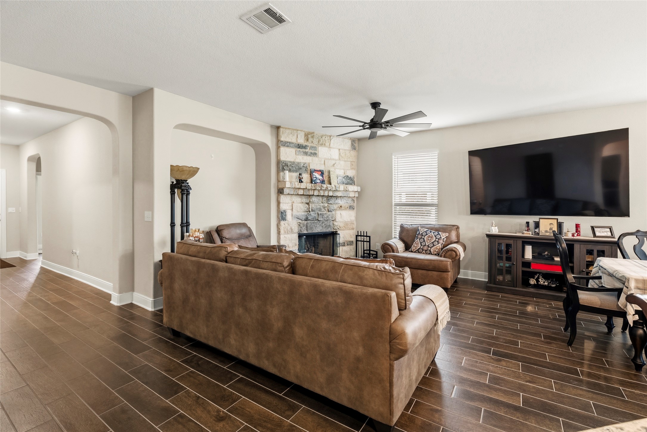 105 West Point Way Elgin, TX 78621 - Photo 18 of 27 Spacious living area featuring wood-finish flooring, a stone fireplace, recessed lighting, and an arched entry
