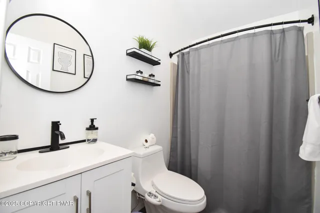 a bedroom with a bed and a large mirror on dresser with wooden floor