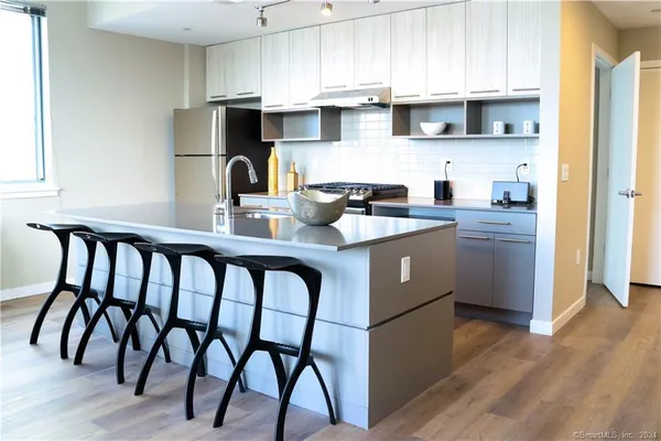 a kitchen with stainless steel appliances granite countertop a kitchen island a stove a cabinets and a refrigerator