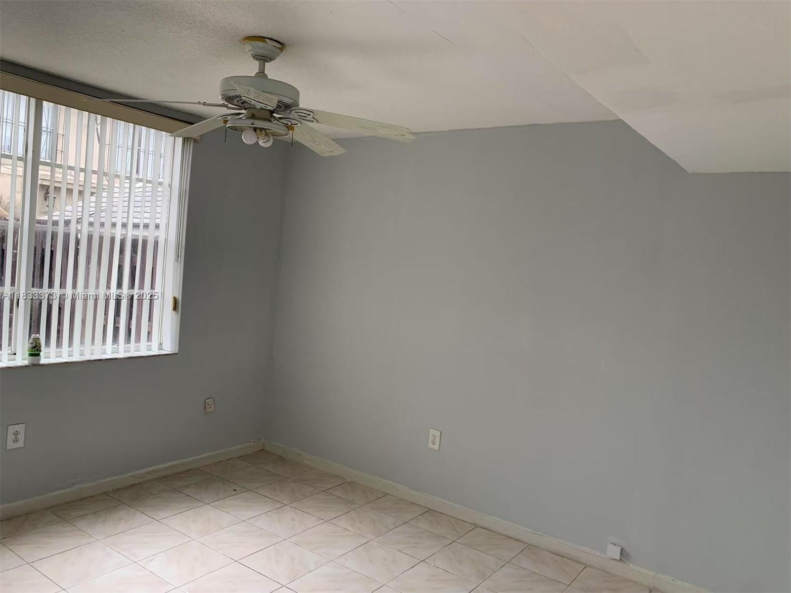 1062 West 42nd Place, Unit STUDIO Hialeah, FL 33012 - Photo 5 of 8 en empty room with windows and chandelier fan