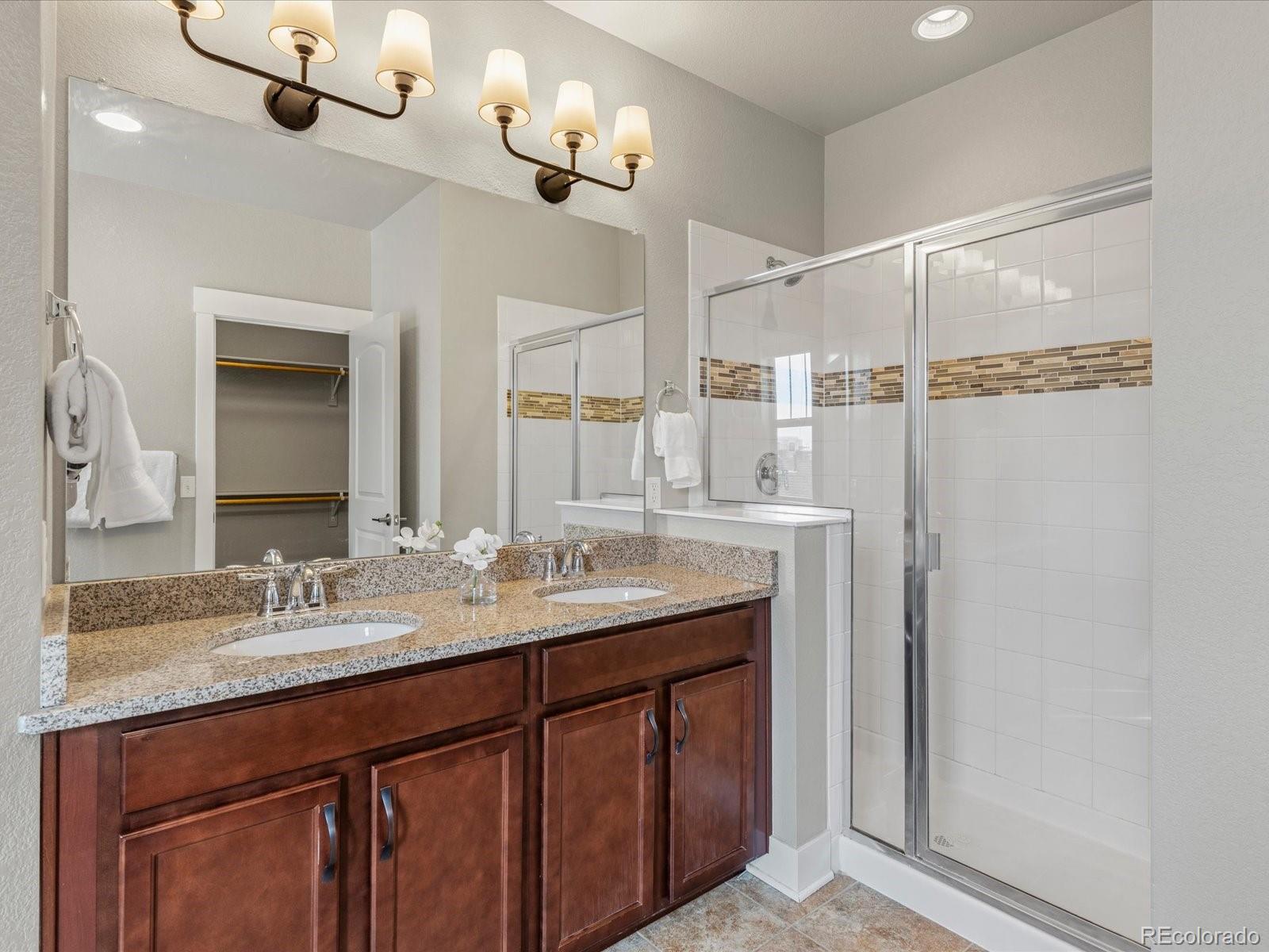 5468 Uinta Way Denver, CO 80238 - Photo 20 of 44 a bathroom with a granite countertop sink a mirror and shower