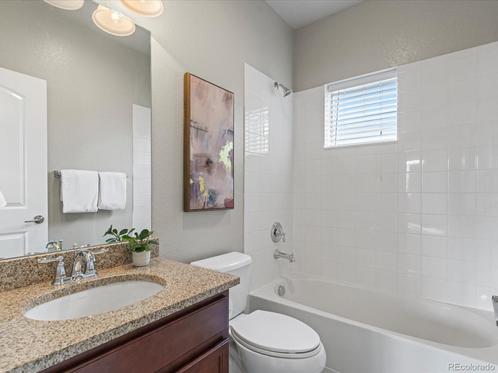 5468 Uinta Way Denver, CO 80238 - Photo 24 of 44 a bathroom with a granite countertop sink a toilet a mirror and shower