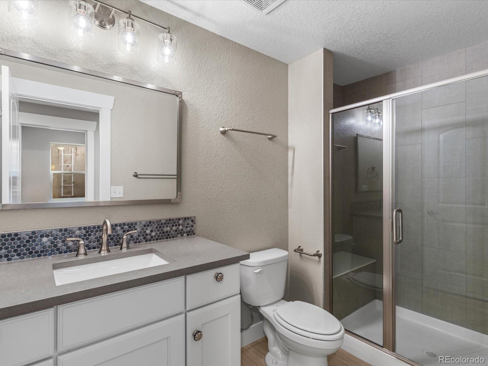 5468 Uinta Way Denver, CO 80238 - Photo 34 of 44 a bathroom with a granite countertop sink a toilet and shower