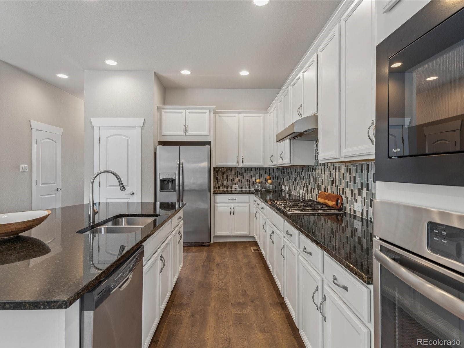 5468 Uinta Way Denver, CO 80238 - Photo 10 of 44 a kitchen with stainless steel appliances granite countertop a sink stove and cabinets