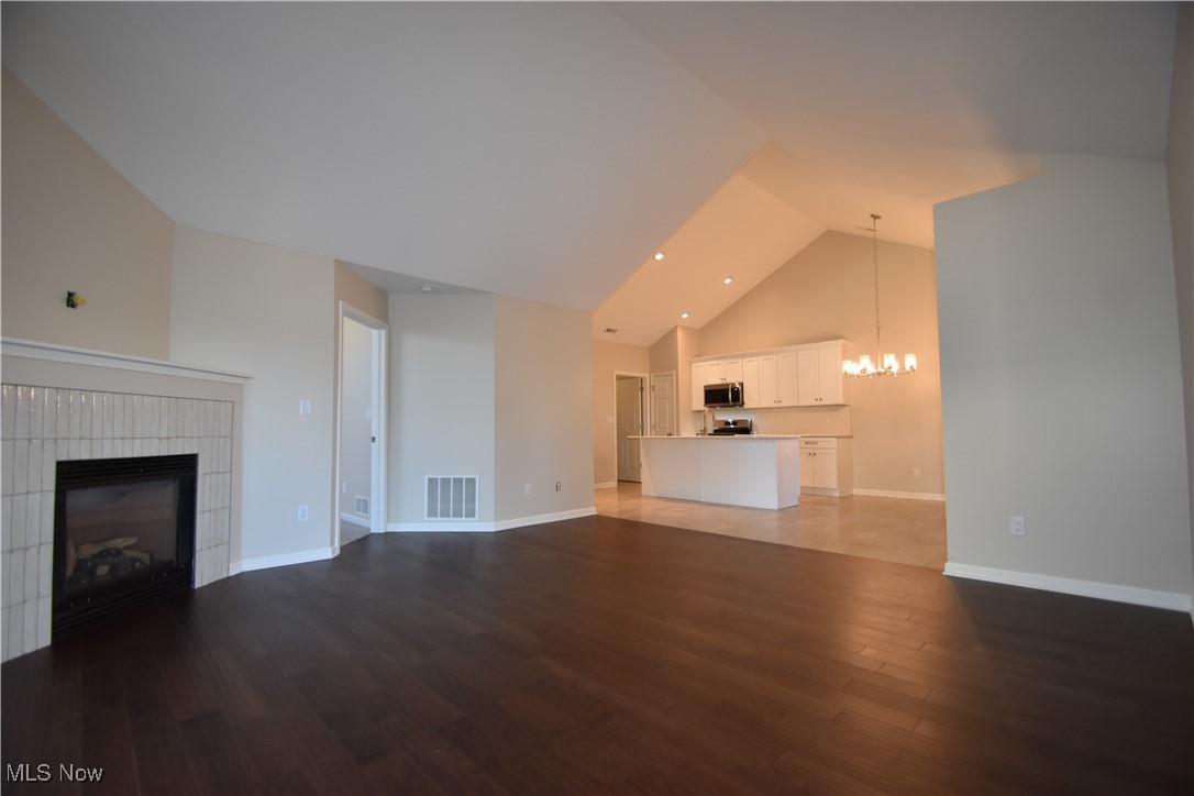9151 Springfield Road, Unit 1002 Youngstown, OH 44514 - Photo 12 of 38 Unfurnished living room with hardwood / wood-style floors, a notable chandelier, a fireplace, and high vaulted ceiling