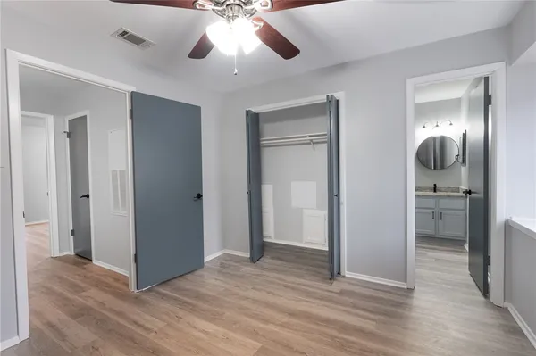 an empty room with wooden floor cabinet and a chandelier fan