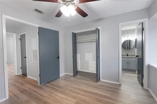 an empty room with wooden floor cabinet and a chandelier fan