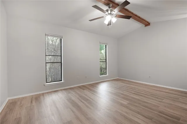 an empty room with windows and fan