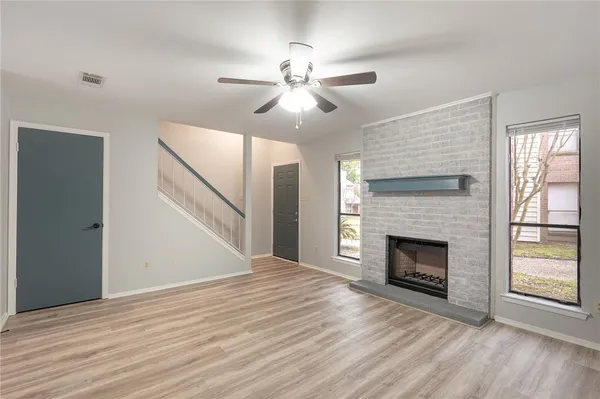 a view of an empty room with wooden floor fireplace and a window