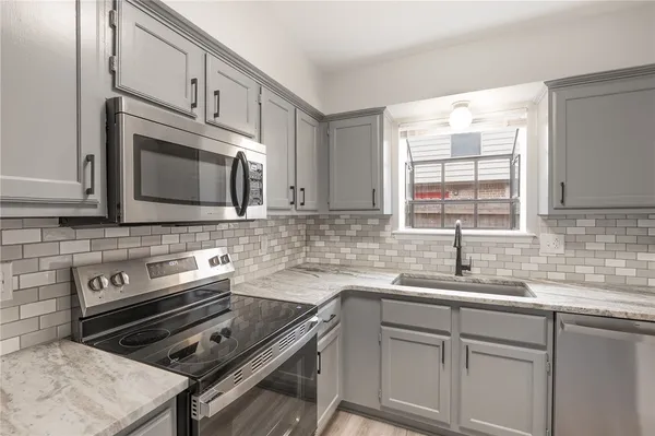 a kitchen with cabinets appliances a sink and a window