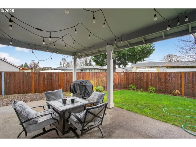 a view of a backyard with table and chairs potted plants with wooden fence