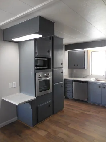 a kitchen with granite countertop stainless steel appliances a sink stove and cabinets
