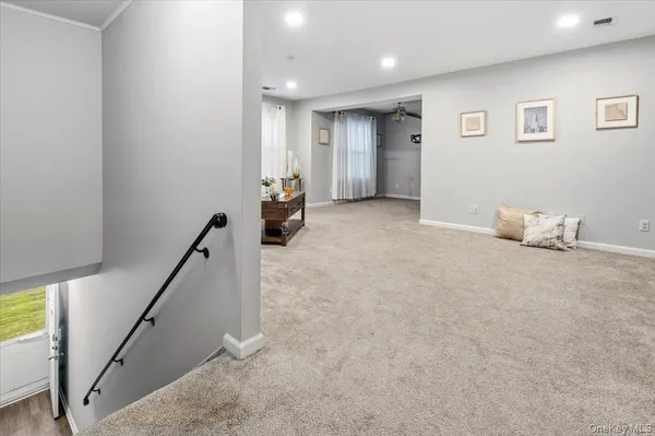a view of an empty room with wooden floor and stairs