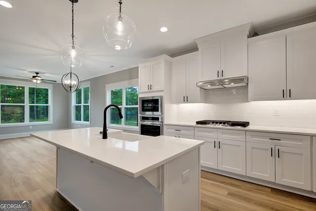 a kitchen with stainless steel appliances granite countertop a sink a stove and a refrigerator
