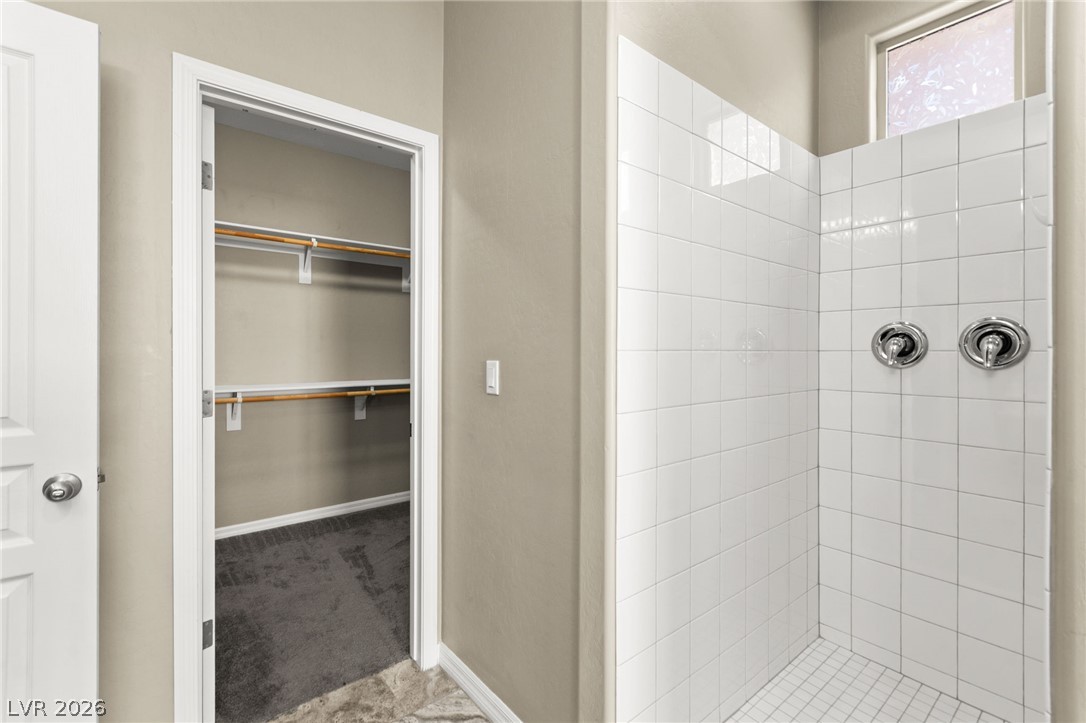 11048 Prairie Grove Road Las Vegas, NV 89179 - Photo 27 of 75 A well-organized walk-in closet adjoins a sleek, tiled shower with modern fixtures and ample natural light.