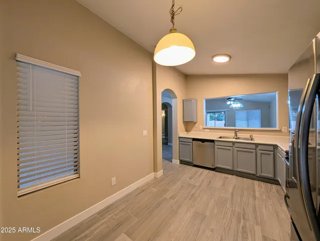 an empty room with wooden floor chandelier and windows