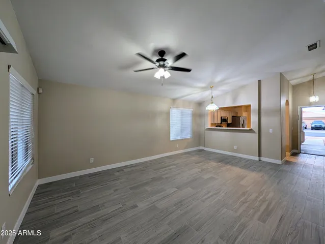 a view of an empty room with window and wooden floor