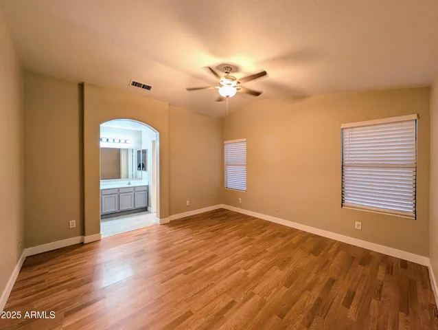 a view of empty room with wooden floor and fan