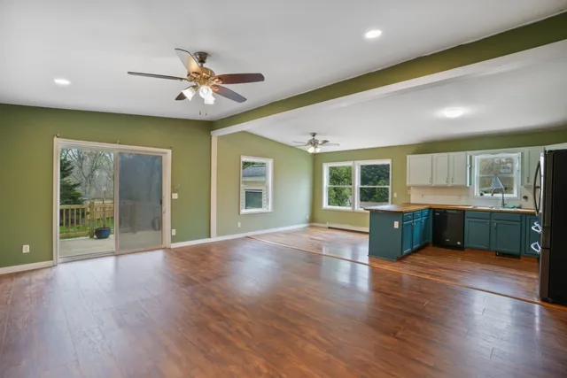 a view of an empty room with window wooden floor and a kitchen