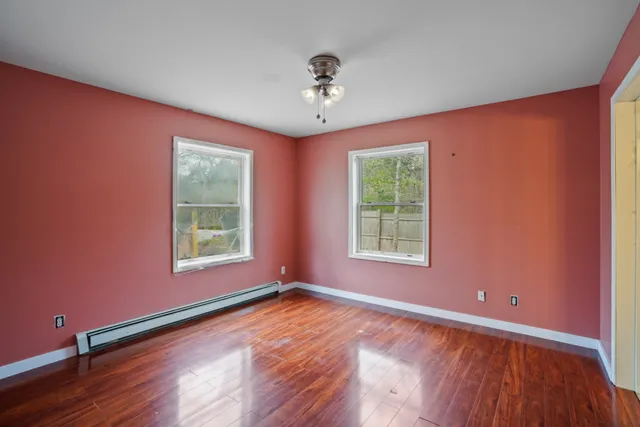 a view of an empty room with a window and wooden floor