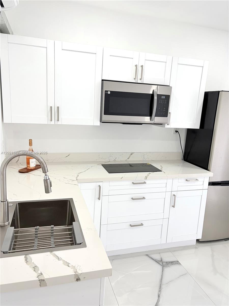 13065 Southwest 263rd Terrace, Unit 2 Homestead, FL 33032 - Photo 8 of 15 a kitchen with a sink a stove and white cabinets