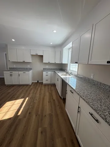 a large kitchen with a lot of counter space and wooden floor