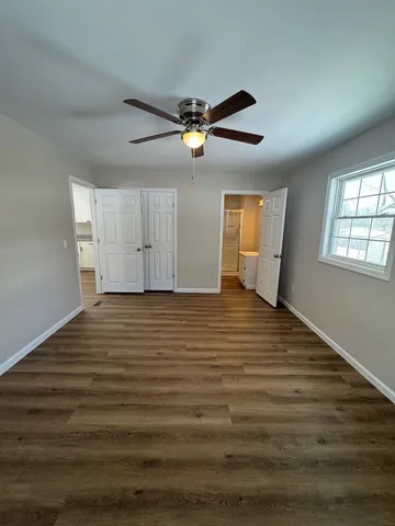 a view of empty room with wooden floor and fan
