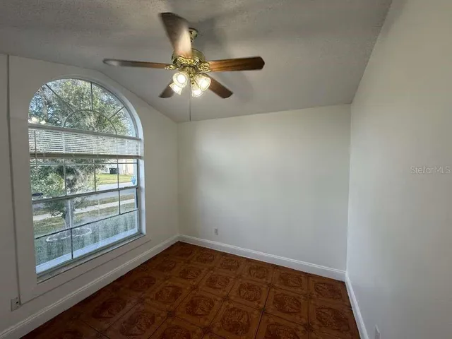 an empty room with wooden floor fan and windows