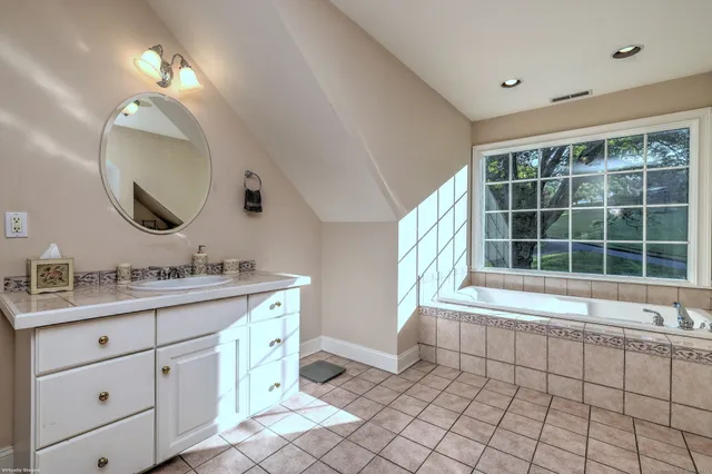a bathroom with a double vanity sink mirror and bathtub