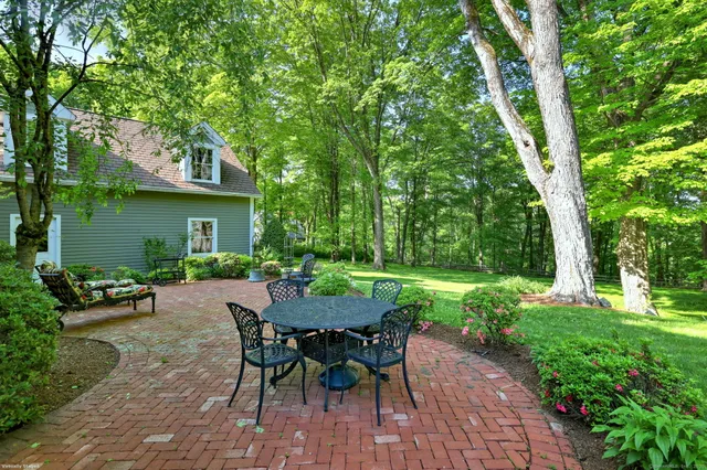 a view of a patio with table and chairs potted plants and large tree