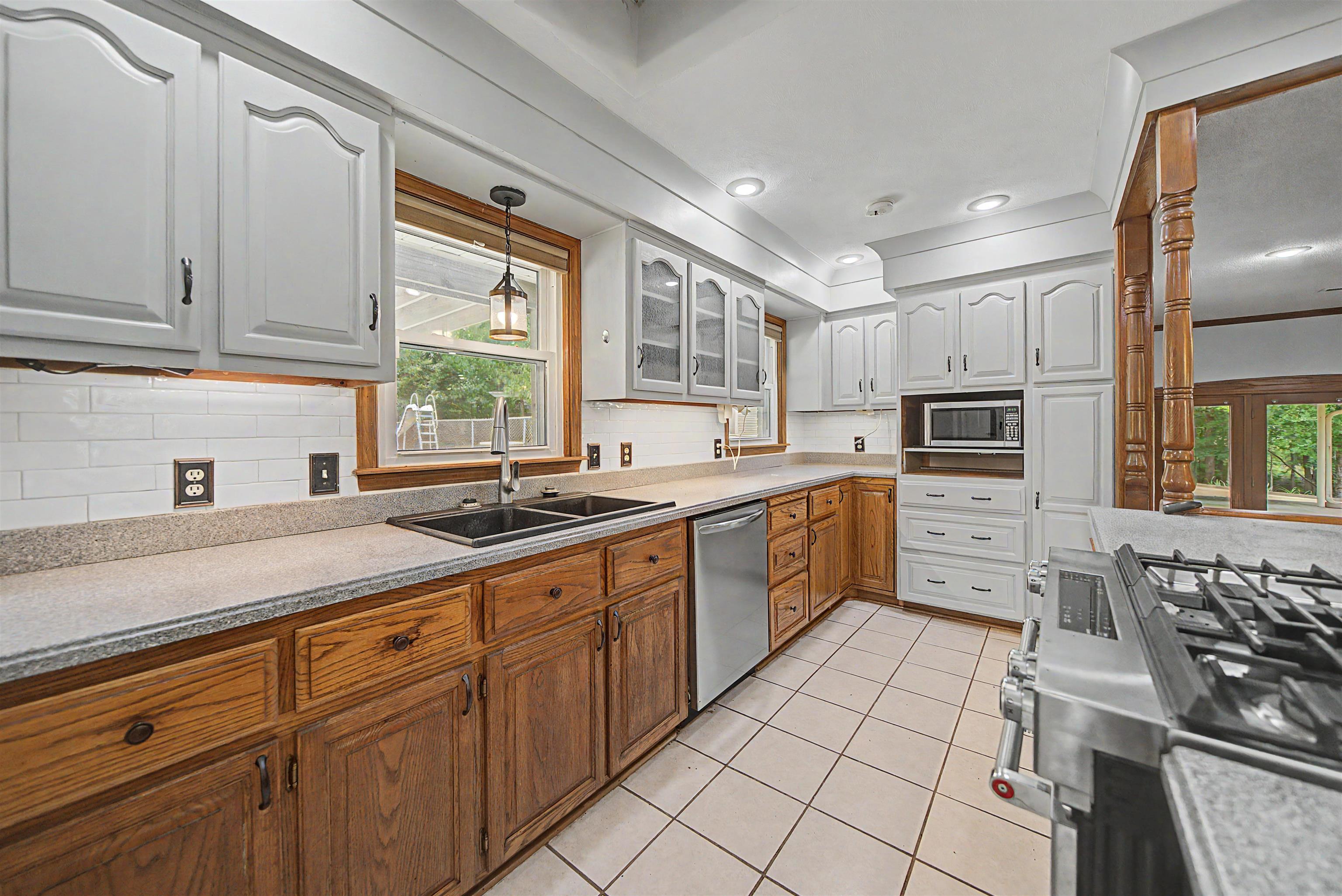 436 Skyline Road Selmer, TN 38375 - Photo 37 of 40 Kitchen featuring two-tone cabinetry, light countertops, subway tile backsplash, and a double basin sink with a modern faucet